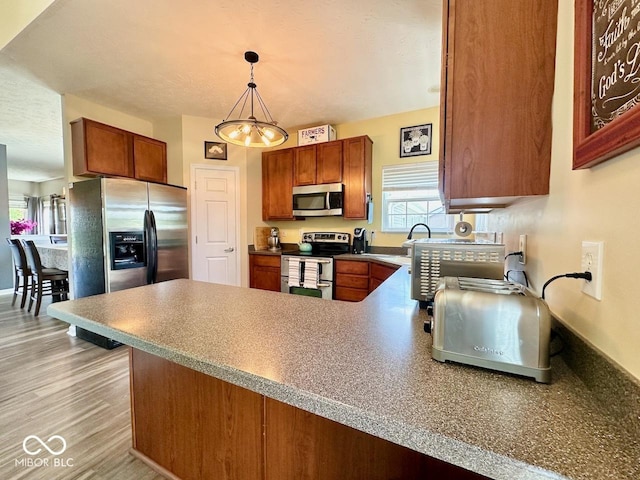 kitchen featuring brown cabinets, a peninsula, appliances with stainless steel finishes, and plenty of natural light