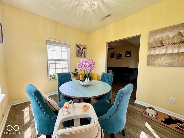 dining room featuring visible vents, a textured ceiling, baseboards, and wood finished floors