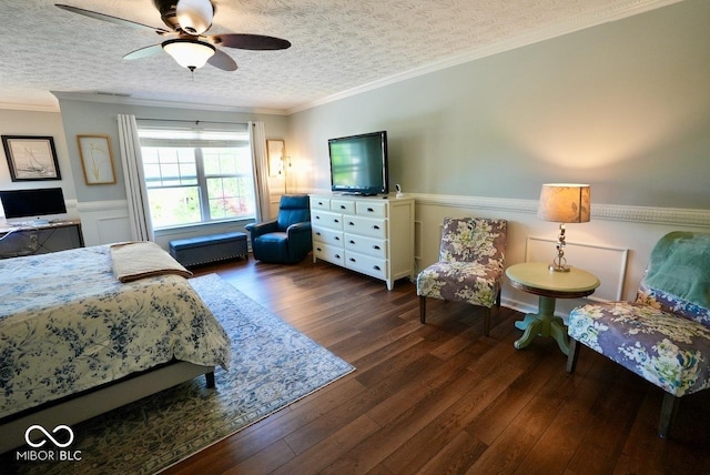 bedroom with crown molding, dark wood-style flooring, wainscoting, a textured ceiling, and a ceiling fan