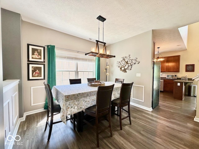 dining space with dark wood-style flooring, baseboards, a notable chandelier, and a textured ceiling