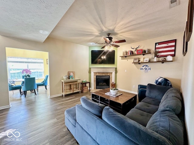 living room with a ceiling fan, baseboards, visible vents, and wood finished floors