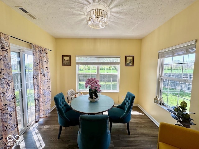 dining area featuring visible vents, a textured ceiling, dark wood finished floors, and a chandelier
