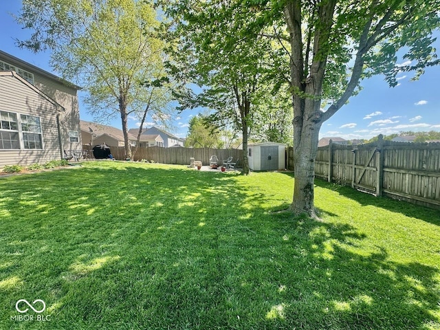 view of yard featuring a storage unit, a fenced backyard, and an outdoor structure
