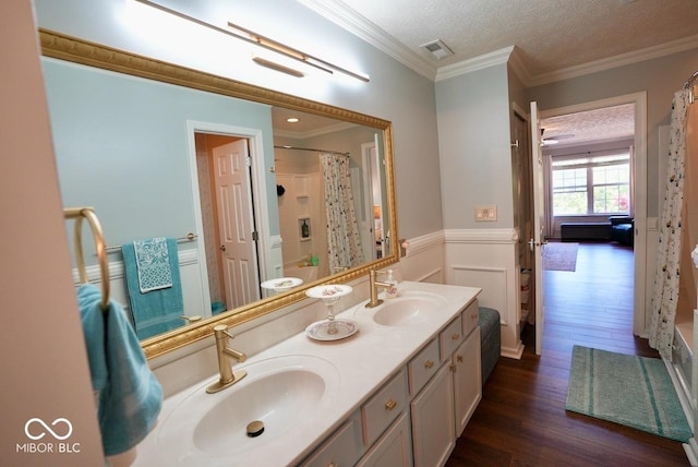 bathroom featuring double vanity, a sink, wainscoting, and wood finished floors