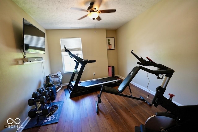 exercise room featuring baseboards, ceiling fan, a textured ceiling, and wood finished floors