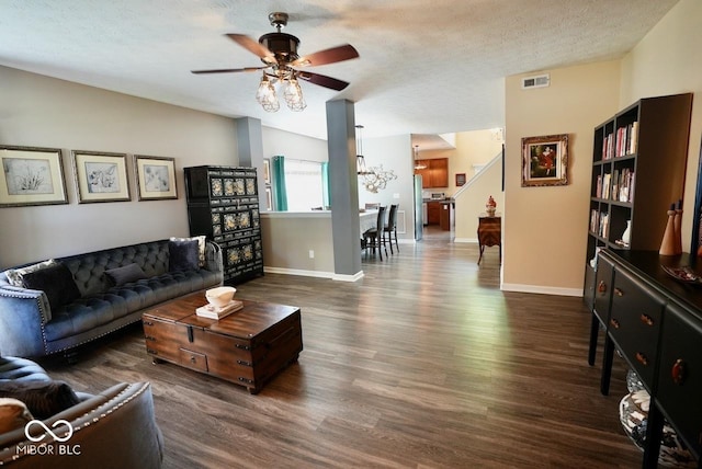 living area featuring ceiling fan, a textured ceiling, baseboards, dark wood-type flooring, and visible vents