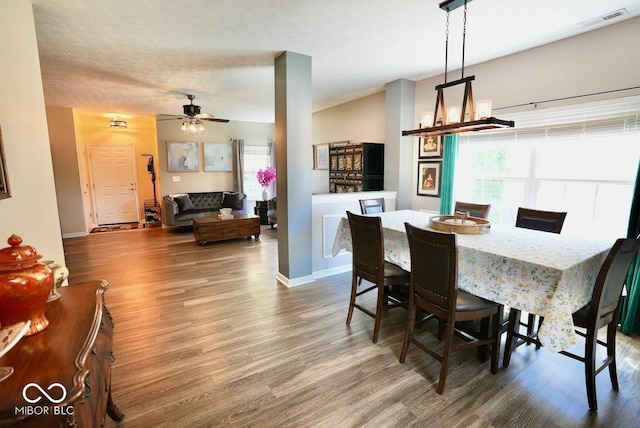 dining space with visible vents, a ceiling fan, baseboards, and wood finished floors
