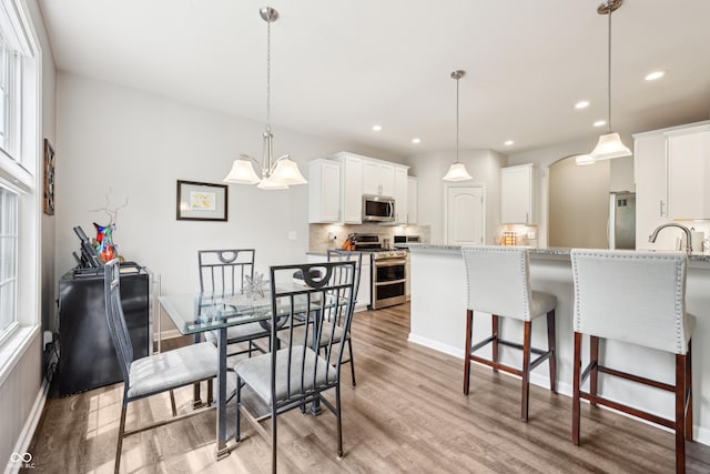 9359 Foudray Cir N, Avon, IN 46123 - dining space with light wood-style flooring, recessed lighting, baseboards, and arched walkways