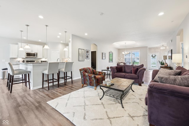 9359 Foudray Cir N, Avon, IN 46123 - living room featuring light wood-style flooring, arched walkways, a chandelier, and recessed lighting