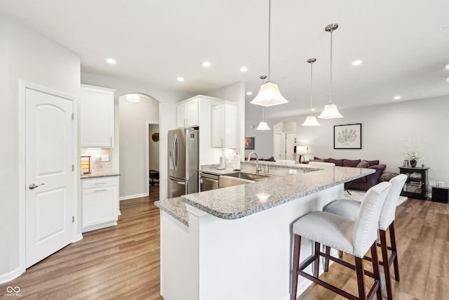 9359 Foudray Cir N, Avon, IN 46123 - kitchen with stainless steel appliances, a sink, arched walkways, light wood-style floors, and a peninsula