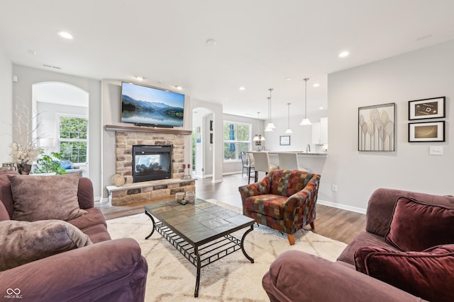 9359 Foudray Cir N, Avon, IN 46123 - living room with arched walkways, wood finished floors, a stone fireplace, recessed lighting, and baseboards