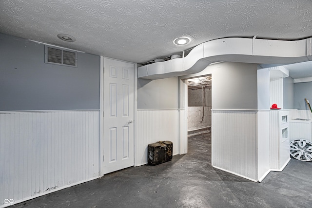 interior space featuring wainscoting, a textured ceiling, and visible vents
