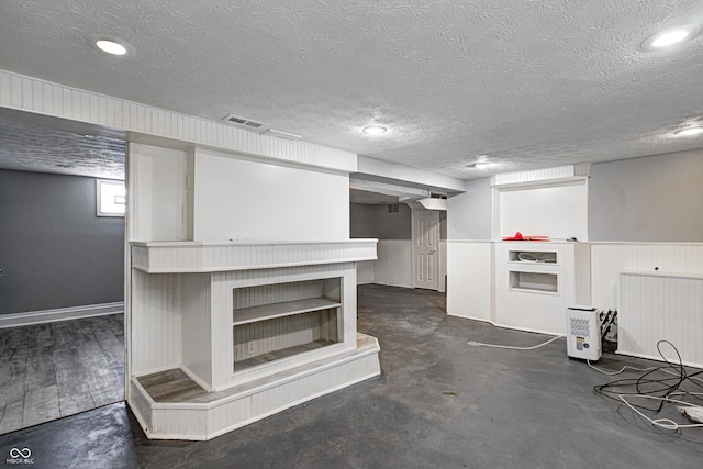 below grade area with visible vents, recessed lighting, and a textured ceiling