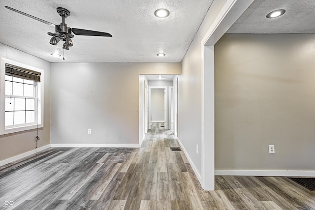 empty room featuring baseboards, a textured ceiling, ceiling fan, and wood finished floors