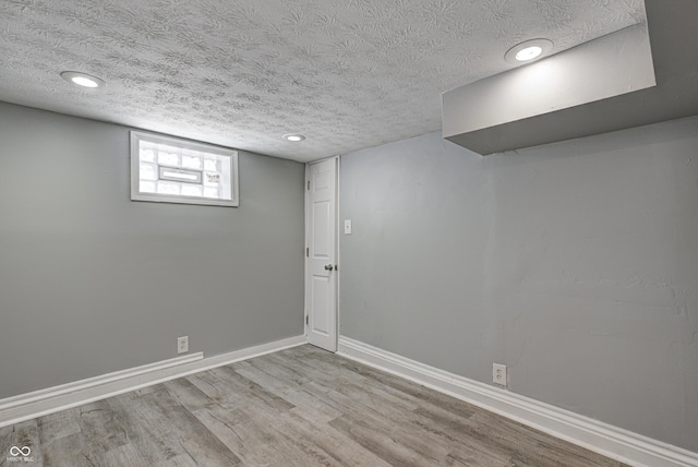 basement featuring baseboards, recessed lighting, a textured ceiling, and wood finished floors