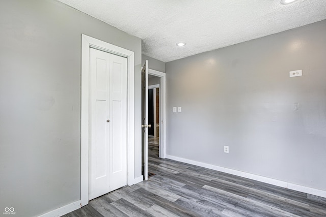 unfurnished bedroom featuring recessed lighting, baseboards, wood finished floors, and a closet