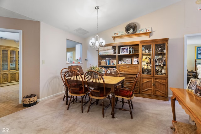 dining room with an inviting chandelier, carpet floors, visible vents, lofted ceiling, and baseboards