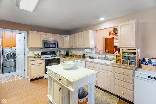 kitchen with washer / dryer, white dishwasher, stainless steel microwave, range with gas cooktop, and a sink