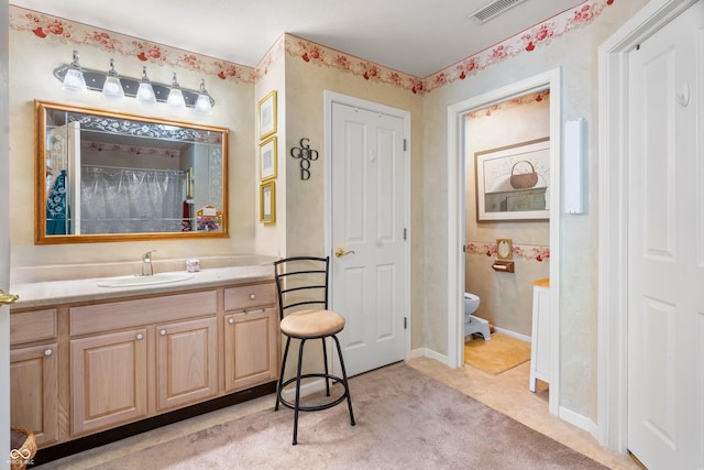 bathroom with vanity, toilet, and visible vents