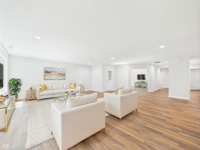 living room with recessed lighting, baseboards, and light wood-style flooring