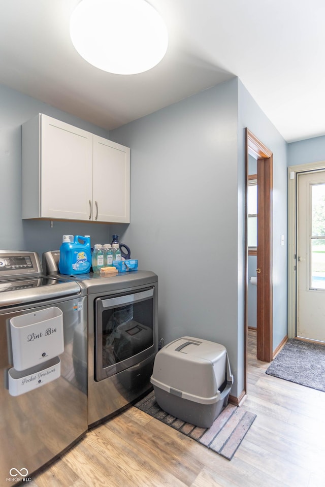 laundry area featuring light wood-type flooring, cabinet space, and washing machine and clothes dryer