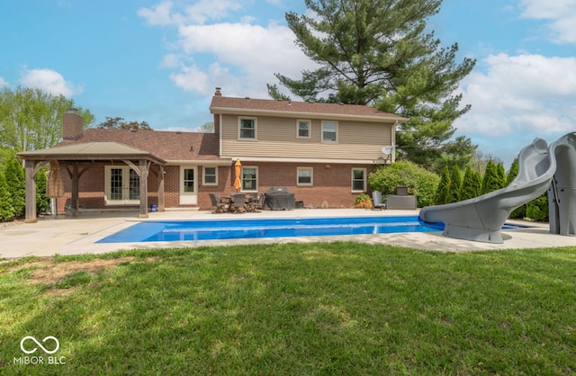 back of property with a lawn, brick siding, a gazebo, and an outdoor pool