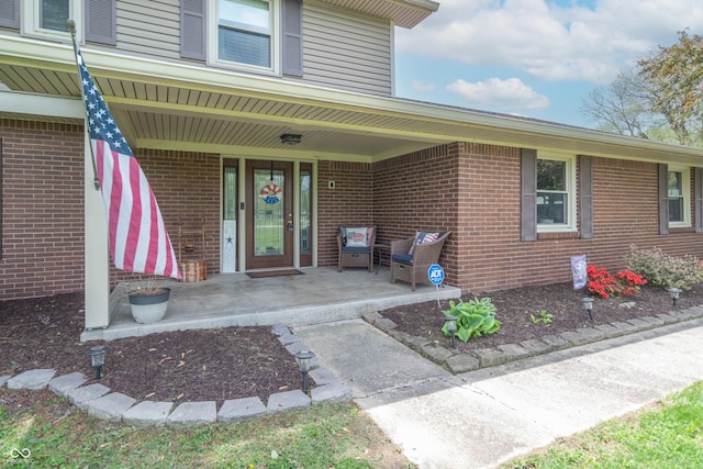 view of exterior entry featuring covered porch and brick siding