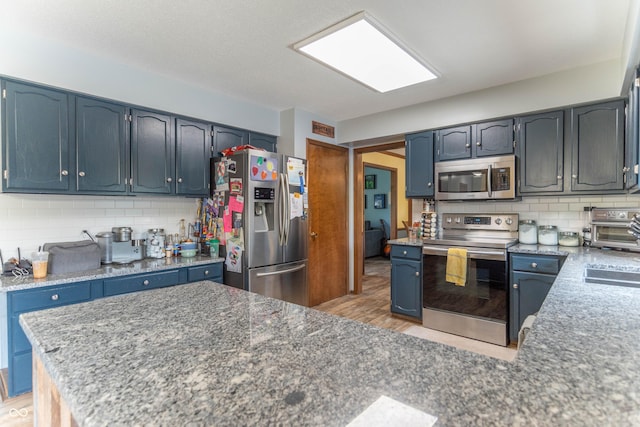kitchen with a peninsula, a toaster, light wood-type flooring, backsplash, and stainless steel appliances