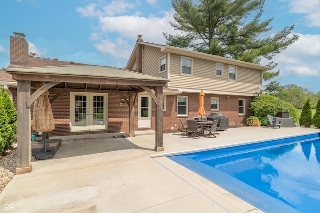 rear view of property featuring brick siding, a chimney, and a patio