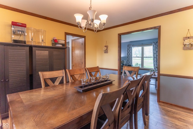 dining area featuring crown molding, baseboards, wood finished floors, and a notable chandelier