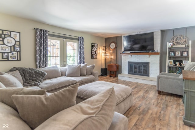 living area featuring a brick fireplace, french doors, and wood finished floors