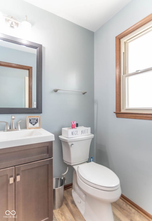 bathroom with toilet, baseboards, wood finished floors, and vanity