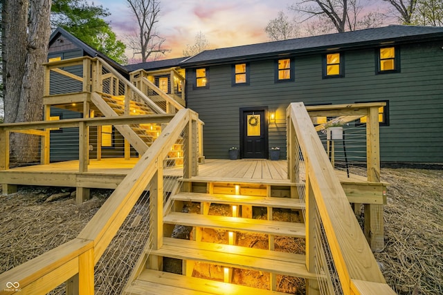 back of house with roof with shingles, a wooden deck, and stairway