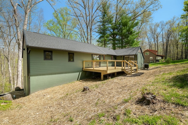rear view of house with roof with shingles, central AC, and a deck