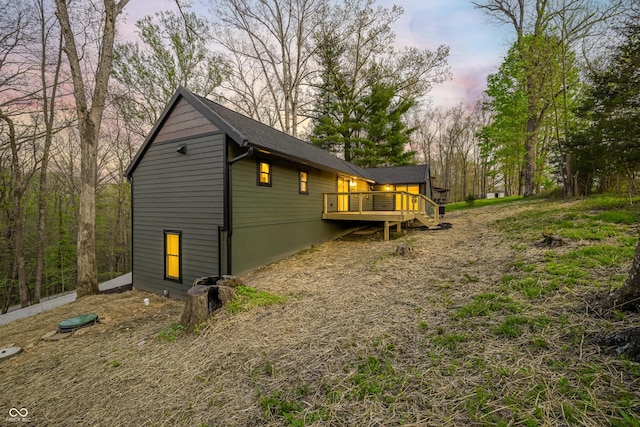 property exterior at dusk featuring a wooden deck