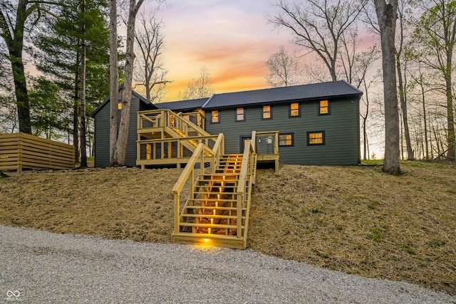 view of front facade with a wooden deck, stairs, and a shingled roof