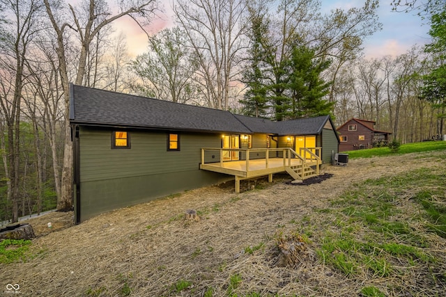 back of house featuring roof with shingles, central AC, and a deck
