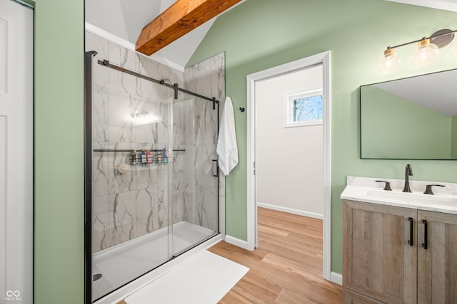 bathroom featuring vanity, wood finished floors, baseboards, a marble finish shower, and vaulted ceiling