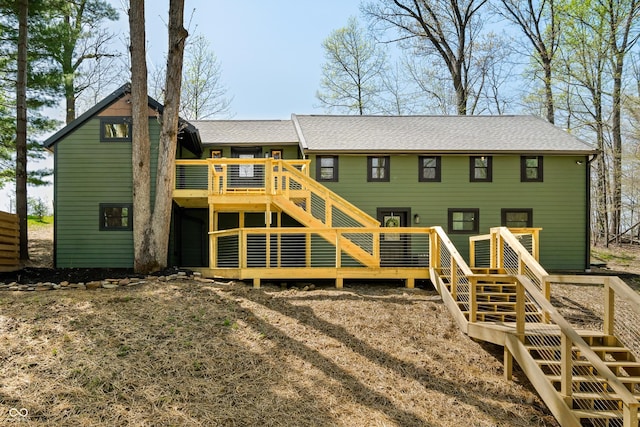 rear view of property featuring roof with shingles, a deck, and stairway