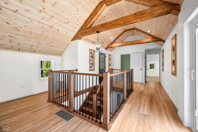 corridor featuring visible vents, light wood finished floors, an upstairs landing, and wooden ceiling