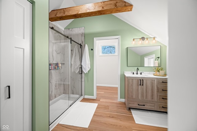bathroom with vanity, wood finished floors, baseboards, lofted ceiling with beams, and a marble finish shower