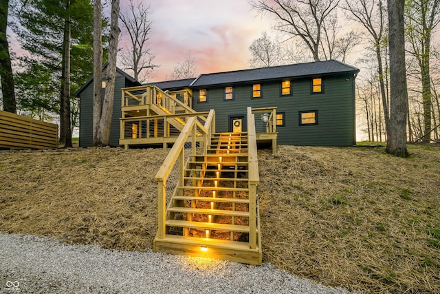 exterior space with stairway, a wooden deck, and a shingled roof