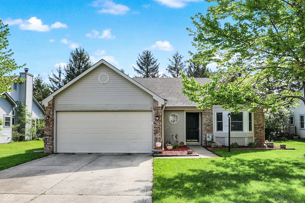 ranch-style home featuring roof with shingles, a front yard, a garage, brick siding, and concrete driveway