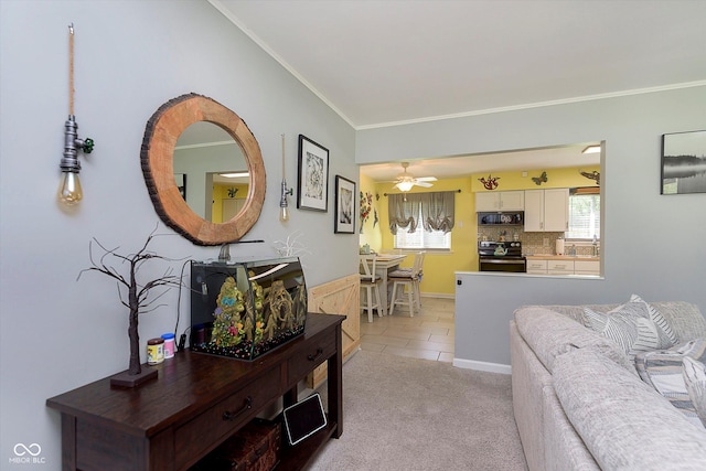 living room featuring crown molding, a ceiling fan, light colored carpet, and light tile patterned floors
