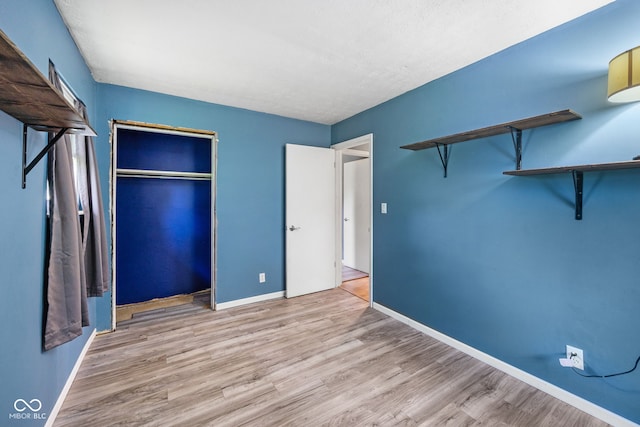unfurnished bedroom with a closet, wood finished floors, and baseboards