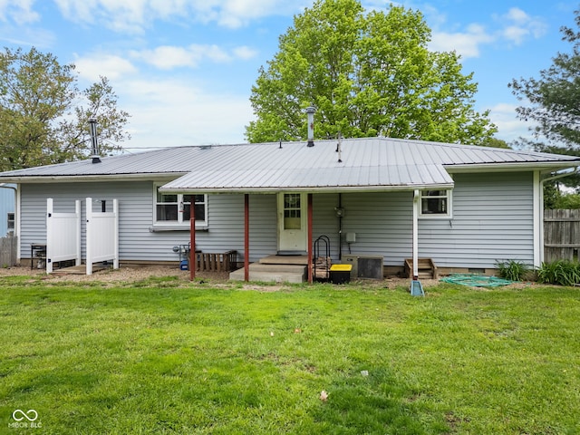 back of house featuring a yard, metal roof, and fence
