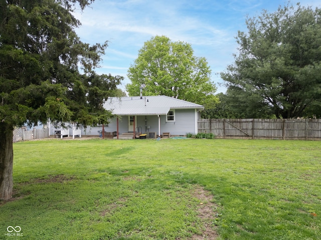 rear view of house featuring a lawn and a fenced backyard