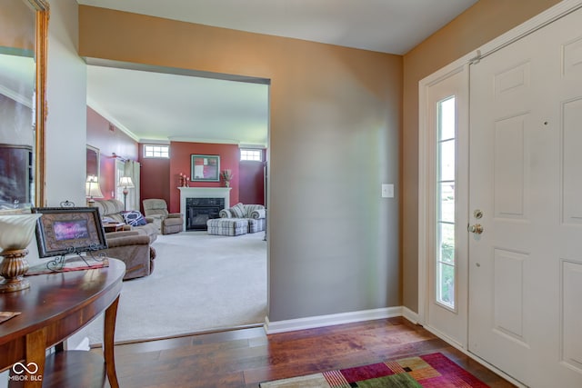 entrance foyer featuring crown molding, baseboards, a glass covered fireplace, and wood finished floors