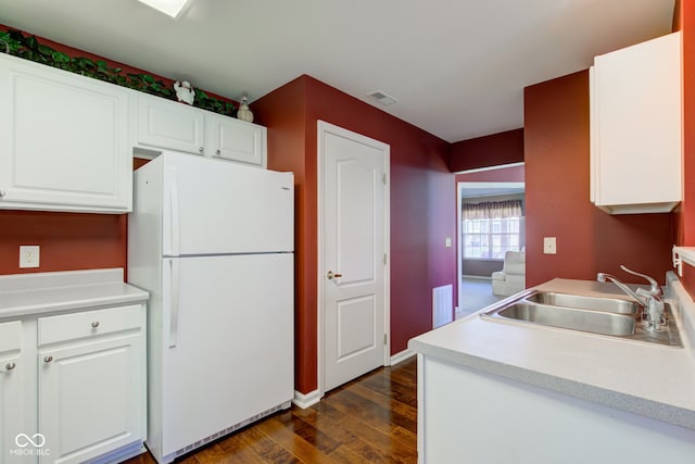 kitchen with freestanding refrigerator, dark wood-style flooring, light countertops, white cabinets, and a sink