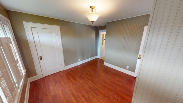 spare room featuring crown molding, baseboards, and wood finished floors